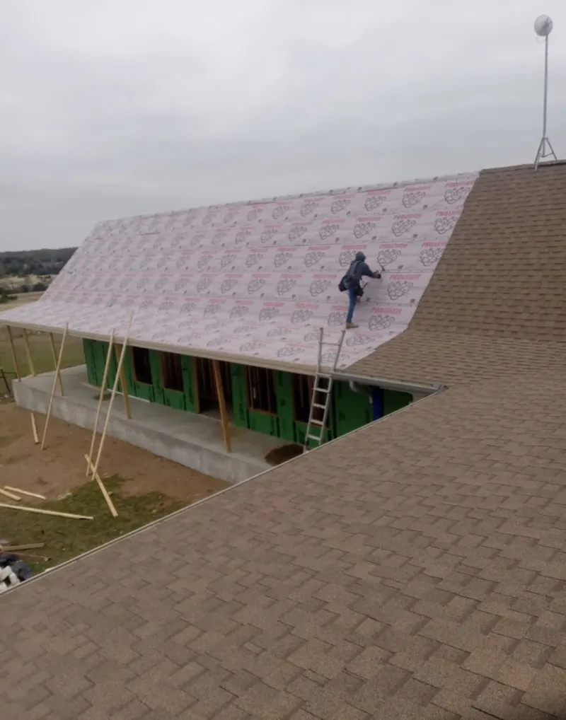 Worker preparing underlayment for a metal roof installation in Whitefish Bay
